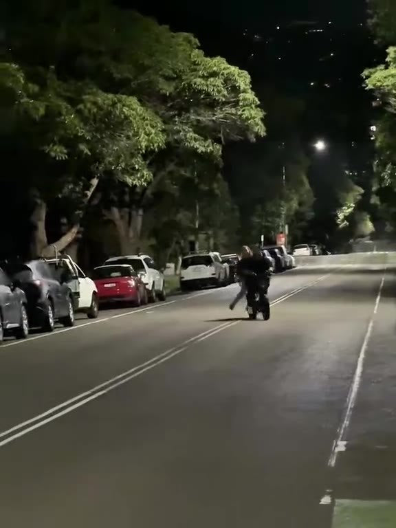 Two people riding a bicycle together down a quiet night street